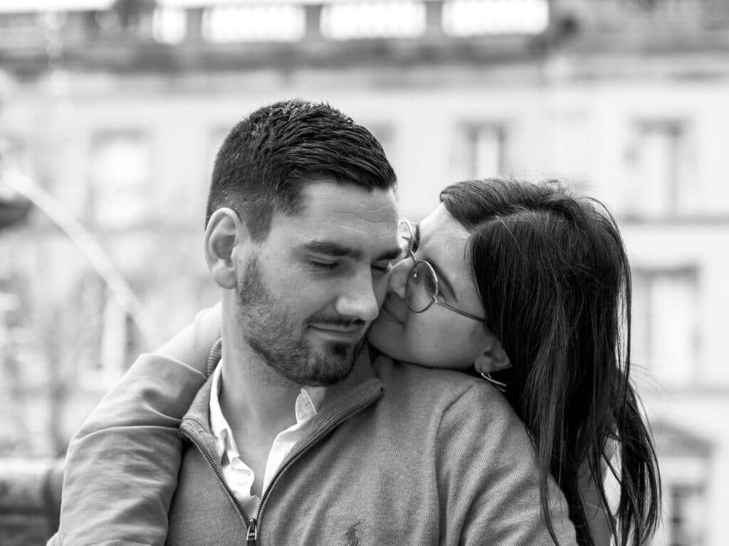 séance phgoto couple Place Carnot à Carcassonne les amoureux sont assis au pied de la fontaine Neptune. Ils s'enlacent. Il ferme les yeux pendant qu'elle le regarde amoureusement.