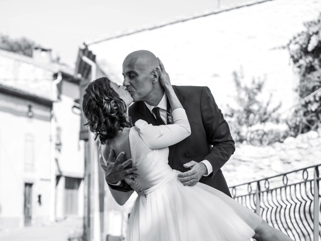 séance photo de couple mariage civil photo de la mariée et du marié en train de s'embrasser. La mariée porte une robe courte Pronuptia pour mariage civil. Le marié porte un costume The Kooples.